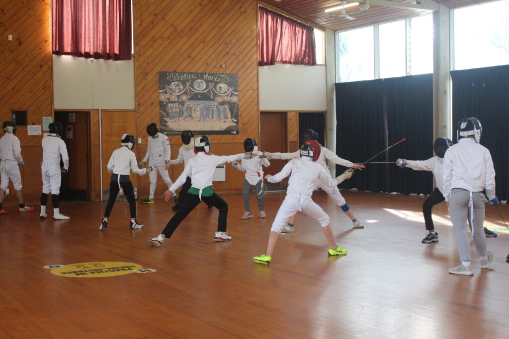 Two rows of fencing students, practicing basic hits